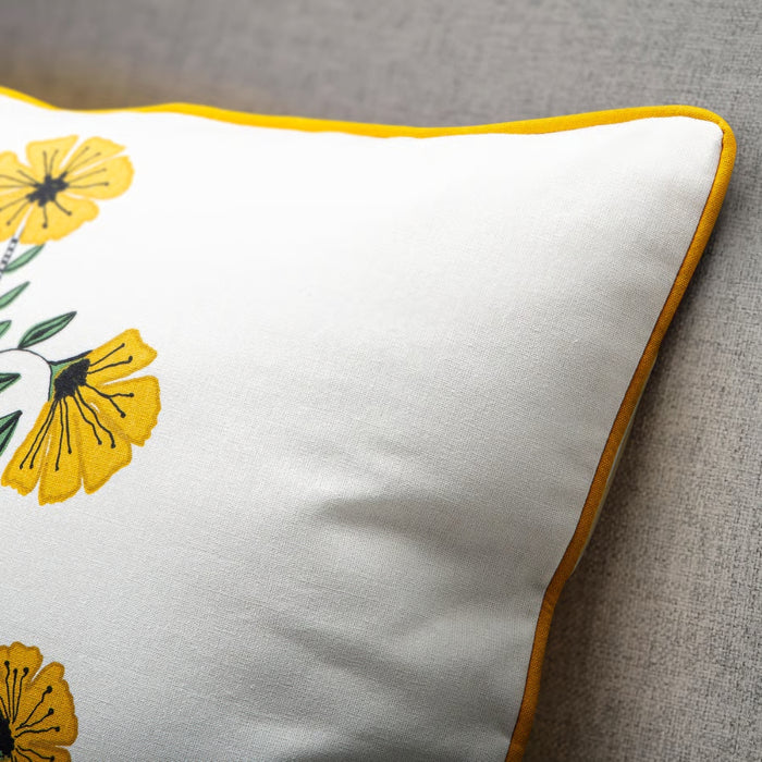 White pillow with yellow floral patterns on a gray surface