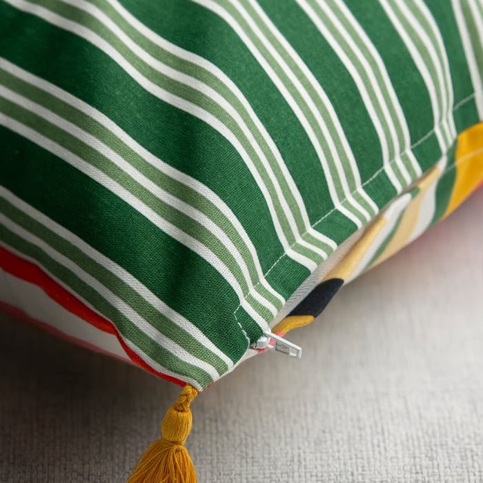 Close-up of a green and white striped fabric with a yellow tassel on a neutral background