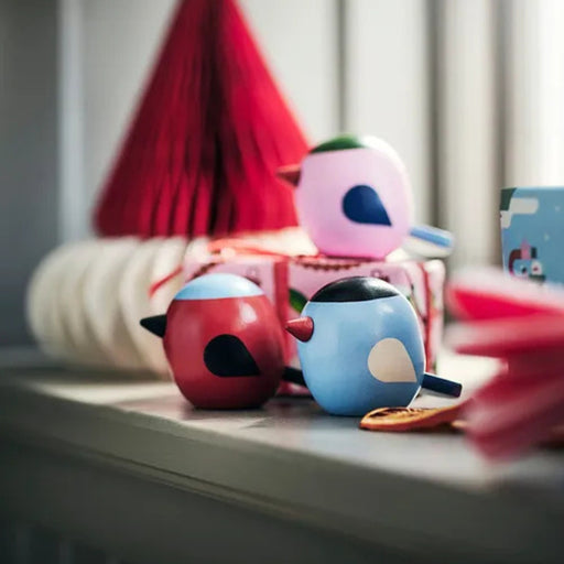 Two colorful bird-shaped figurines on a shelf with a blurred background