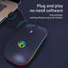 Gaming mouse with RGB lighting on a dark surface, connected to a laptop.