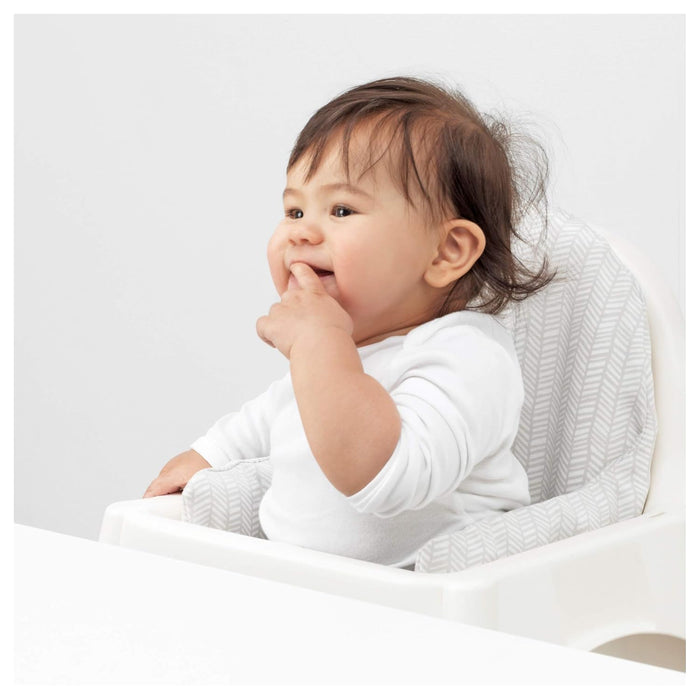 Baby sitting on a white surface with a neutral background