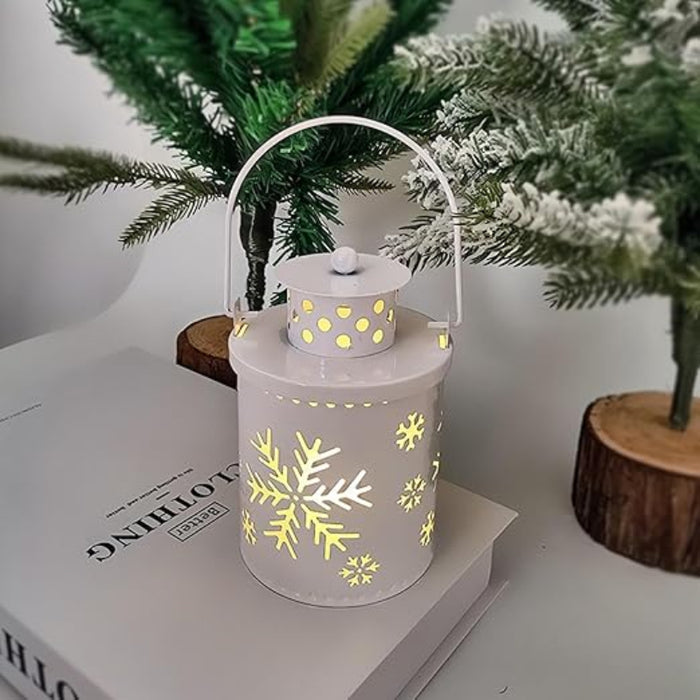 Decorative lantern with snowflake patterns on a book next to a Christmas tree.
