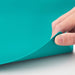 Hand holding a turquoise sheet of paper against a teal background