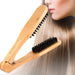 Wooden hairbrush with black bristles being used on a person's hair against a white background