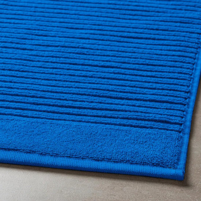 Close-up of a blue textured rug on a neutral background