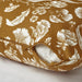 Close-up of yellow-brown cushion cover with white floral design and partially open zipper – 20570990