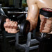 Person holding two dumbbells with a blurred gym background