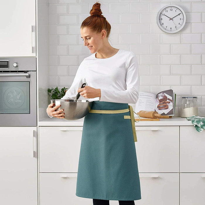 Woman in a kitchen wearing a teal apron, holding a mixing bowl.