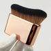 gold rectangular makeup brush with gradient bristles presented in hand photography