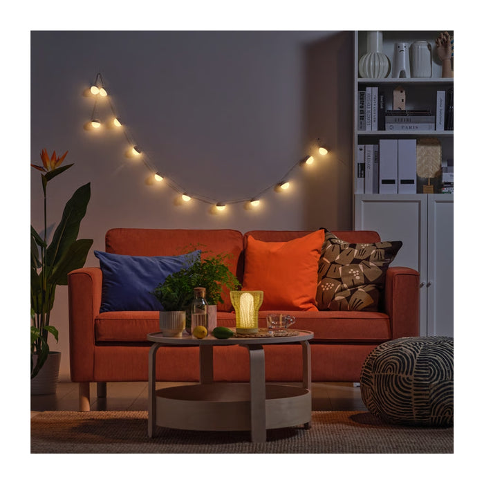 Cozy living room with an orange sofa, string lights, and decorative items.