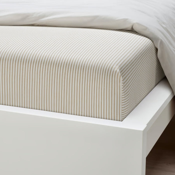Beige striped fitted sheet on a white bed frame