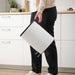 Lifestyle shot of a person carrying the pedal bin in a kitchen with white cabinets.