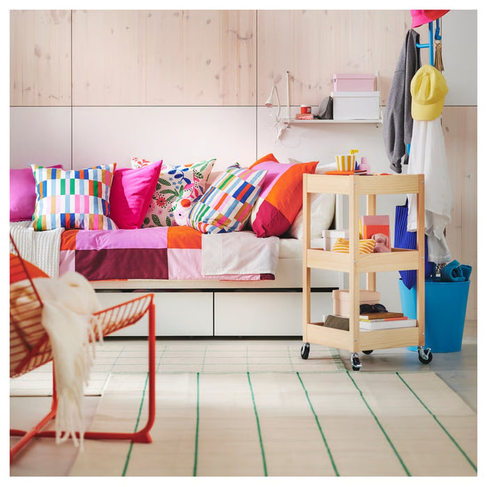 LOSHULT trolley in colorful bedroom corner, holding boxes, books, and pencils in front of patchwork quilt daybed with decorative pillows
