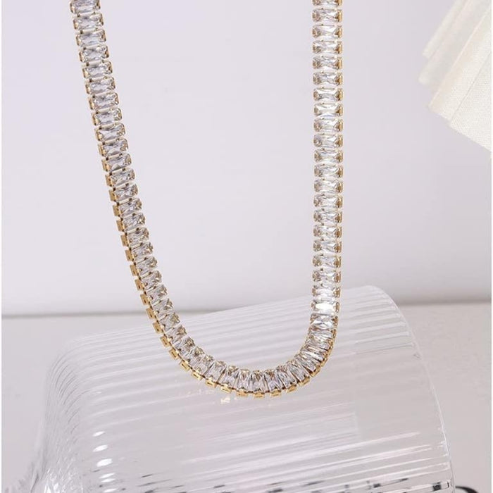Gold rhinestone necklace – matching rectangular-cut stones draped over ribbed glass surface
