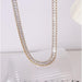 Gold rhinestone necklace – matching rectangular-cut stones draped over ribbed glass surface
