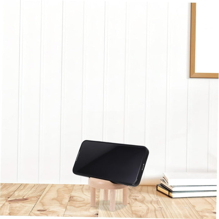 Smartphone placed horizontally on mini wooden chair stand beside stacked books – clean tabletop setup with white panel backdrop – 1598453326009 13953547