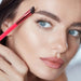 Close-up of woman using red angled eyebrow brush for precise brow shaping – highlights defined lashes, smooth skin, and natural makeup finish – 1598453751840 14041847