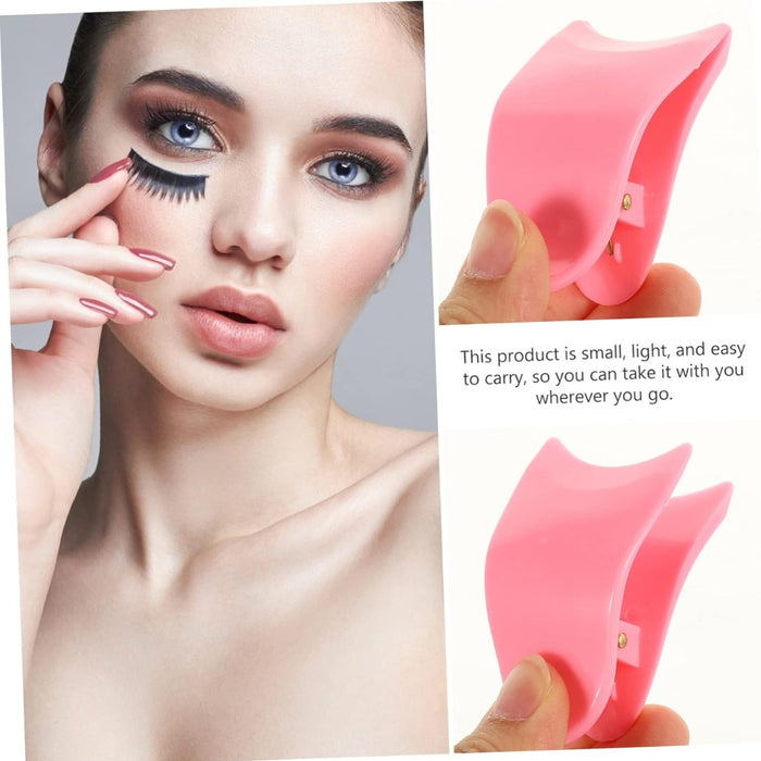 Woman applying false eyelashes with a pink eyelash extension tool on a gray background.