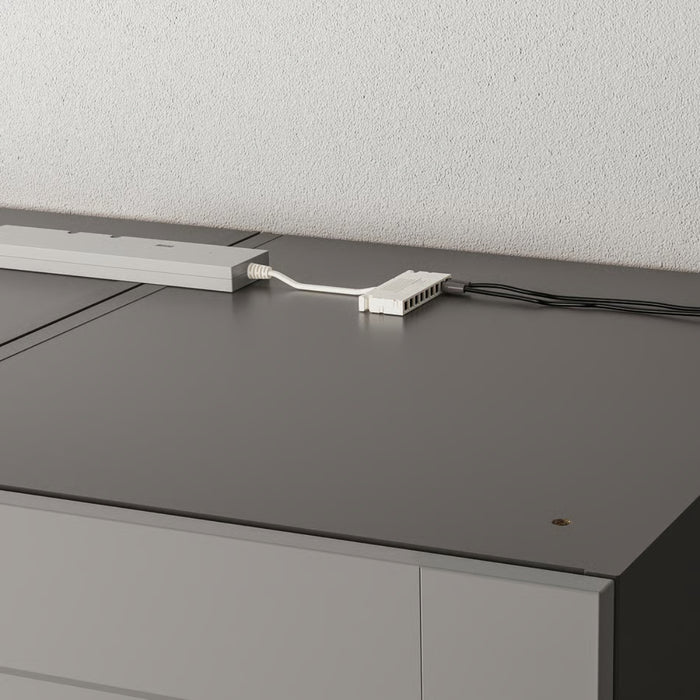 Gray office desk with a power strip and cable on a light gray background