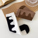 Wave-patterned socks in black/white and brown tones arranged with wooden board and open book