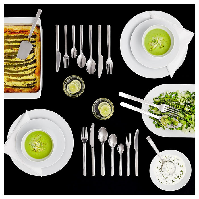 Dinner setting with green soup, pasta, and salad on a black background