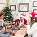 Family celebrating Christmas with a decorated tree and festive table setting.
