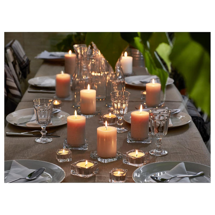Dining table set with candles and glasses, surrounded by greenery