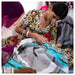 Woman working on a piece of fabric with intricate patterns