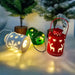 Three decorative lanterns with lights on a surface with a Christmas tree in the background.