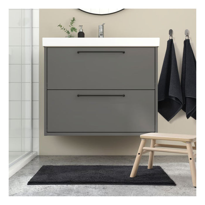 Bathroom with gray vanity unit, black rug, and wooden stool.