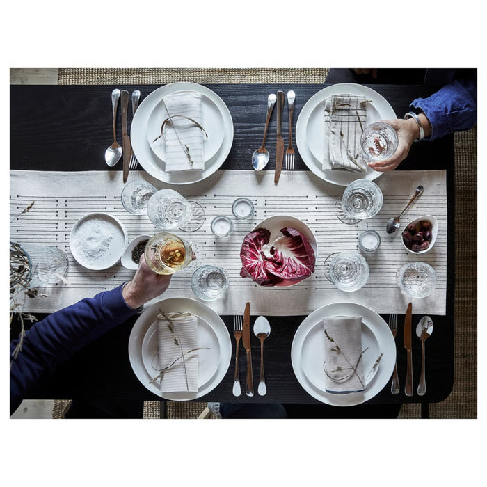 Two people at a dinner table setting with plates, glasses, and cutlery.
