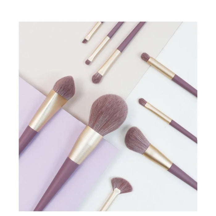 Makeup brushes with purple bristles and gold handles on a light background