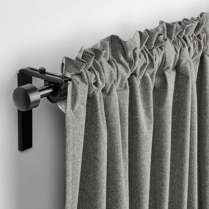 Gray curtain with a black curtain rod on a white wall