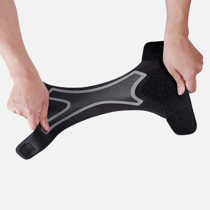 Black ankle brace held in hands to show flexible, ergonomic shape – stretchy material with gray accents and Velcro strap – 1600007421321 13974241
