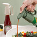 Hand pouring ketchup from a squeeze bottle onto a salad with a green background
