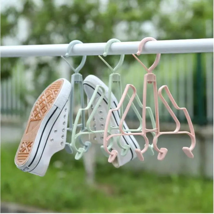 Colorful plastic hangers with shoes on a clothesline against a blurred green outdoor background