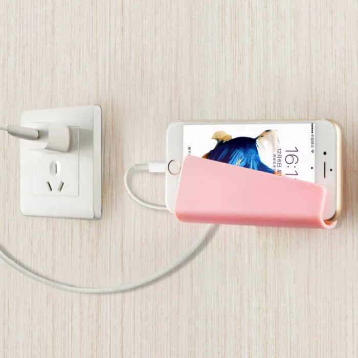 Phone with a pink power bank connected to a wall outlet on a light wooden surface