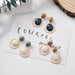 Pair of earrings with wooden and bead designs on a white surface with 'COURAGE' text.