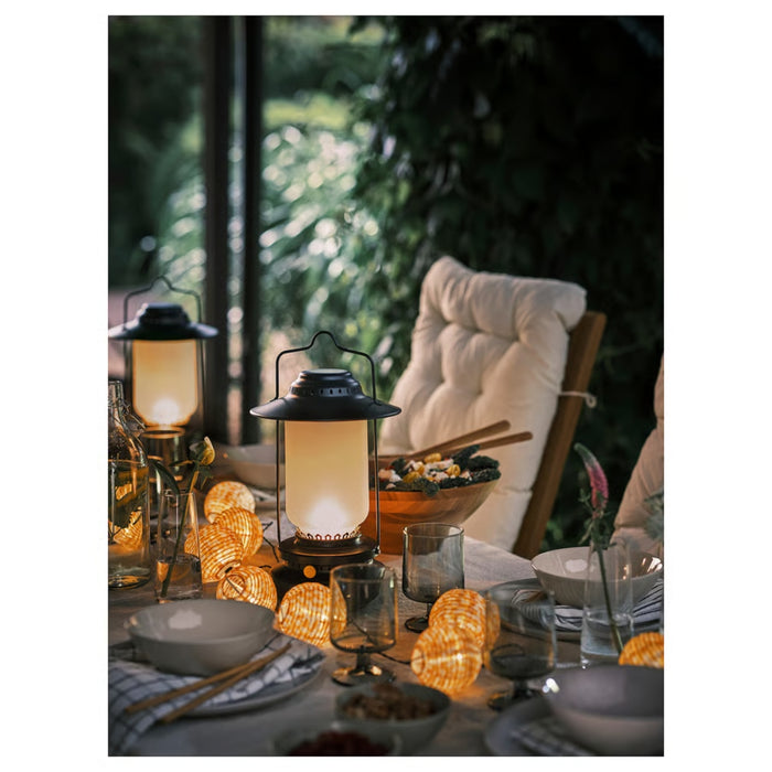 Dining table set with lanterns and string lights in an outdoor setting