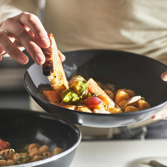 Person dipping bread into a bowl of soup with vegetables