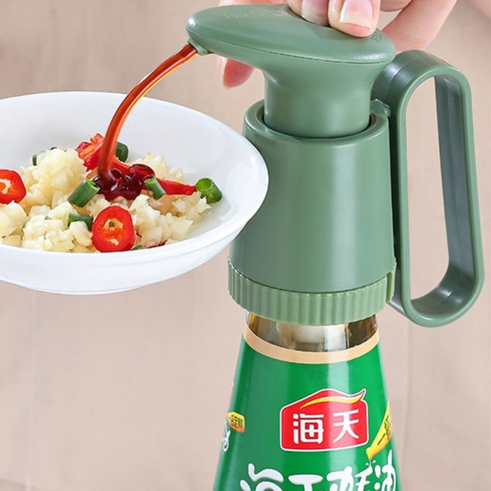 Green bottle with a nozzle being used to pour sauce over a dish of food.