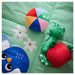 Colorful plush toys on a green blanket with floral patterns