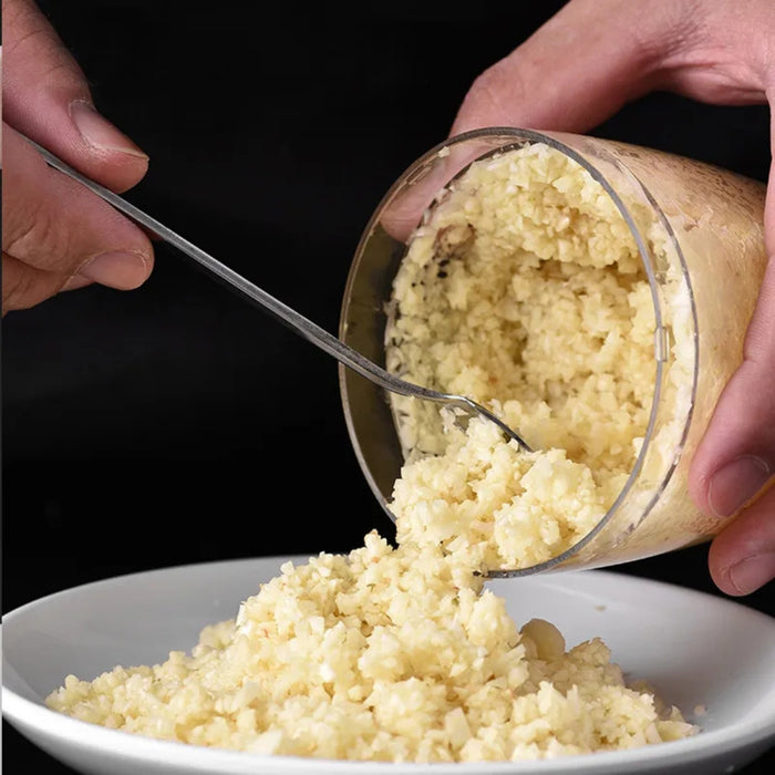 Action shot showing minced garlic being easily scooped out of the clear container for cooking.