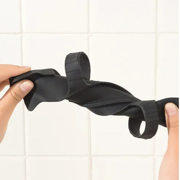 Two hands stretching and twisting a durable black silicone grip strap, showcasing its impressive flexibility and resilience. Set against a white tiled kitchen backdrop, the visual highlights the product’s non-slip, bendable nature—ideal for use with hot cookware, heavy utensils, or as a multi-surface gripping aid.-1598452898401 13017586
