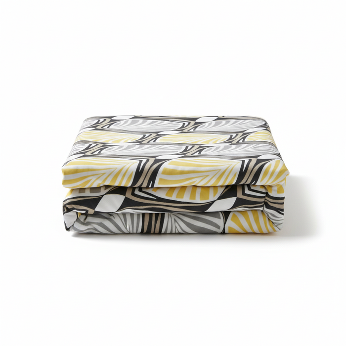 Folded IKEA HÄSTFIBLA bedspread with bold leaf pattern in black, white, gray, and yellow, highlighting its modern textile design