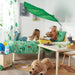 Two kids playing on a bed under the green LÖVA leaf canopy with toys around