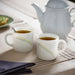 IKEA SKRÄNTÄRNA stripe cups with gold lines beside a grey kettle in a tea setting