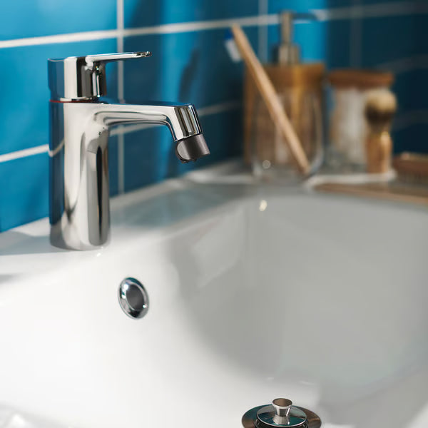 Hands being washed under chrome tap fitted with IKEA ÅBÄCKEN spray nozzle blue sink background