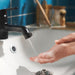 Person washing hands under black mixer tap with ÅBÄCKEN nozzle blue tiled wall backdrop