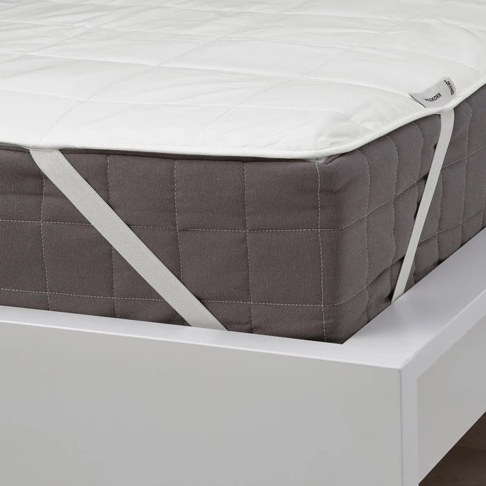 Gray quilted mattress cover on a white bed frame with a visible brand label.